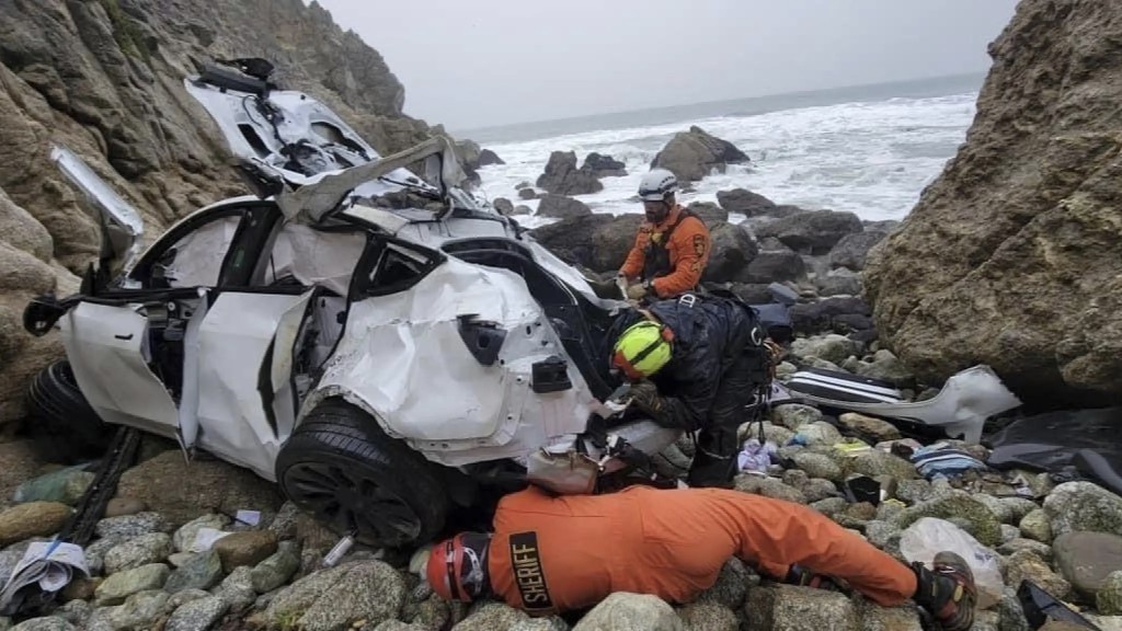 救援人员从堕崖的车内抢救4人。 美联社
