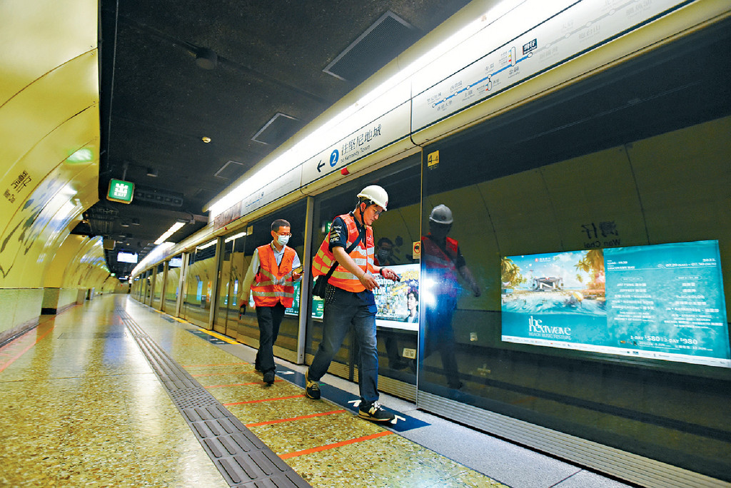■港鐵人員用電筒照射幕門及路軌檢查。 ■港鐵人員用電筒照射幕門及路軌檢查。