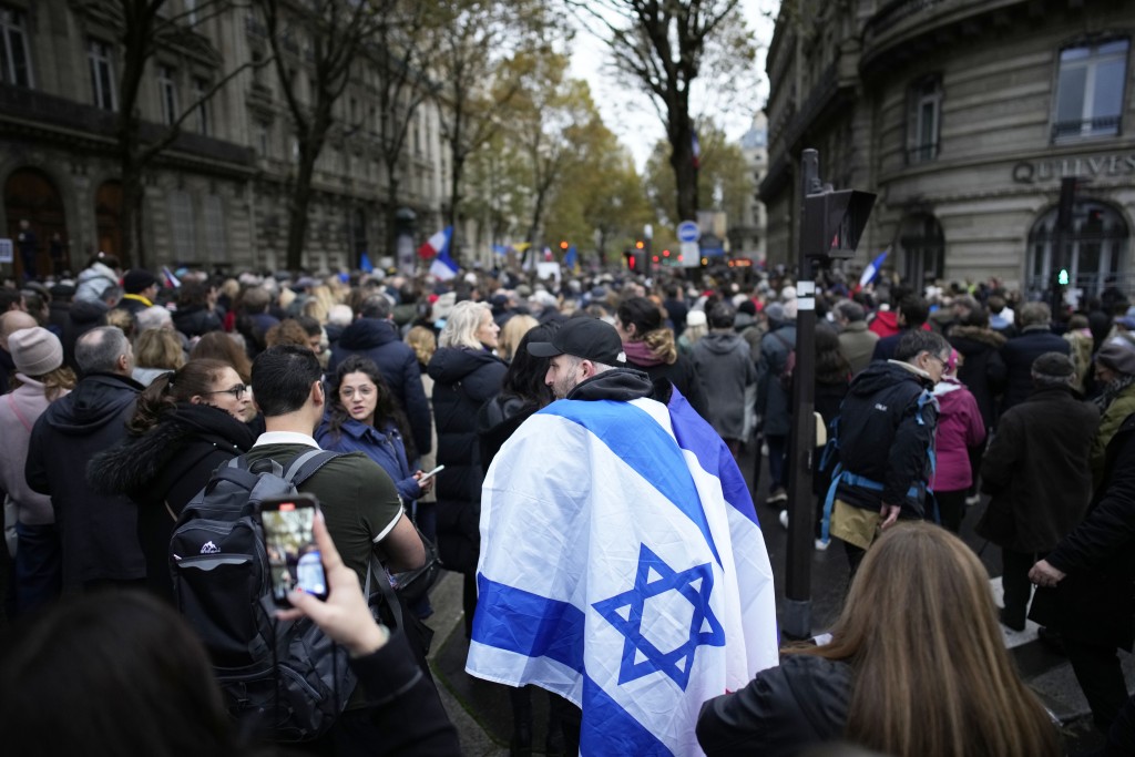 巴黎有參與遊行者披上以色列國旗。美聯社