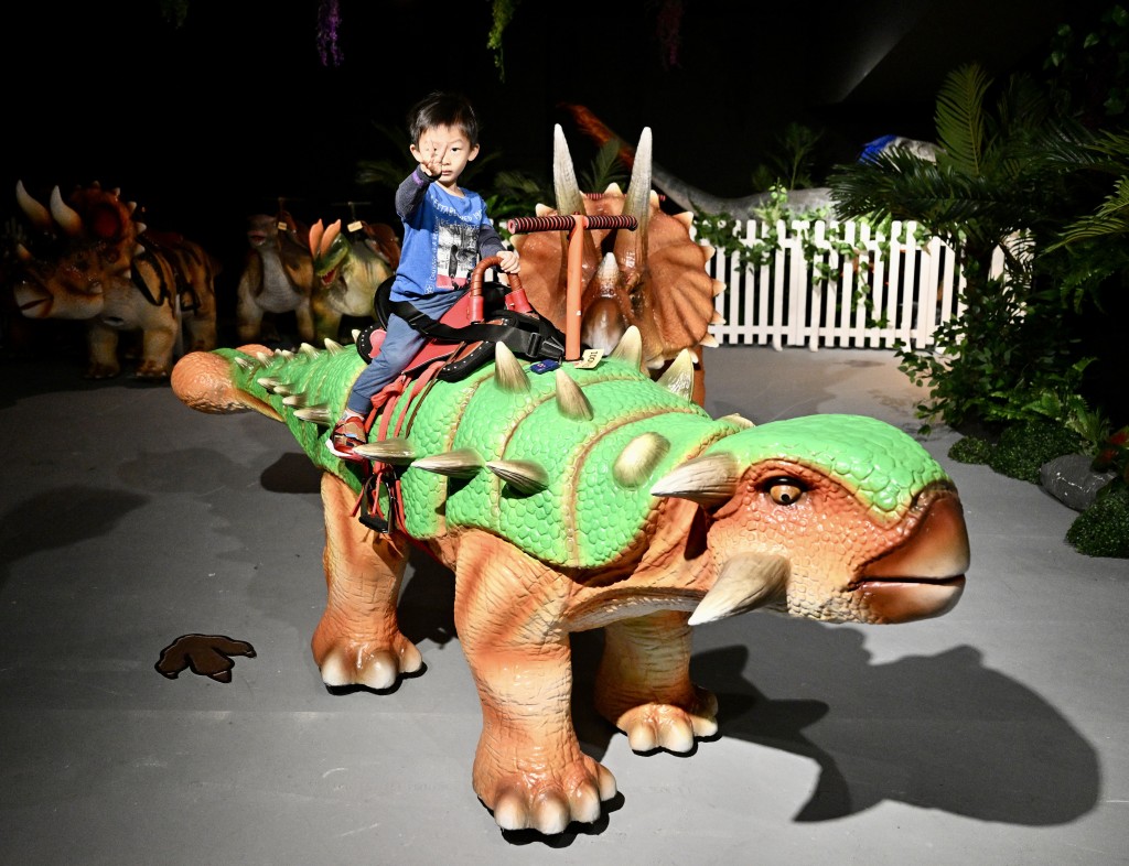 小朋友騎上仿真行走的恐龍，讓工作人員帶領進入侏羅紀時代。（圖片來源：《親子王》）
