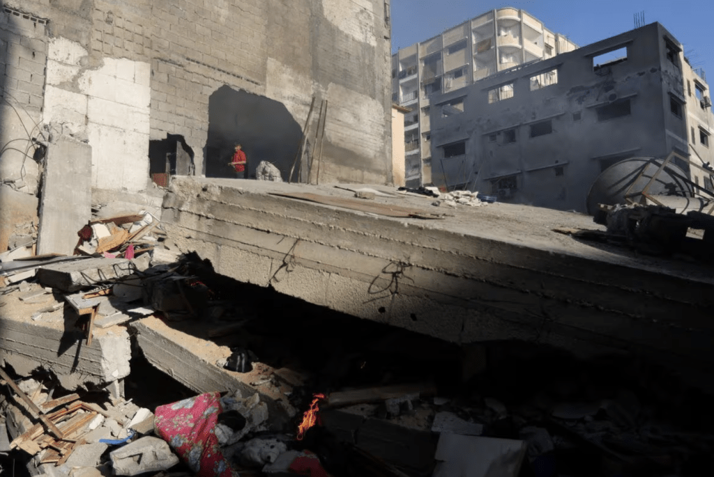 2023 年 12 月 4 日，在加沙走廊南部汗尤尼斯，一名男孩站在以色列袭击中被摧毁的房屋前。路透社