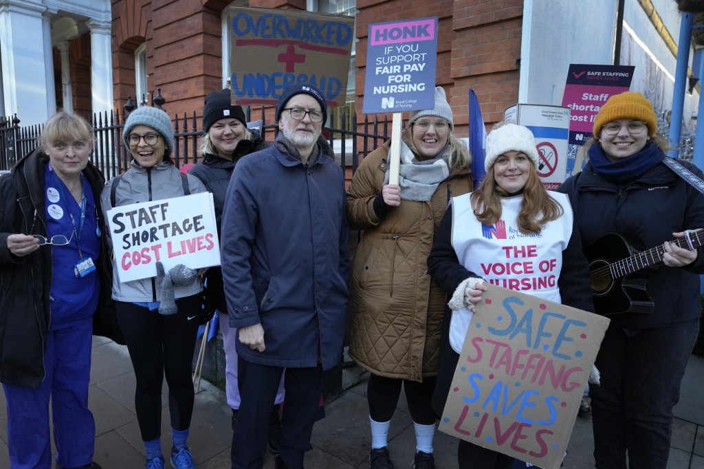 英國工黨前領導人傑里米·科爾賓與罷工護士一起在倫敦大奧蒙德街醫院外的糾察線上合影留念。AP