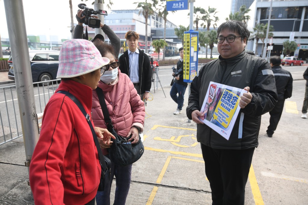 巴士公司職員在站頭提醒乘客上車後要扣安全帶。