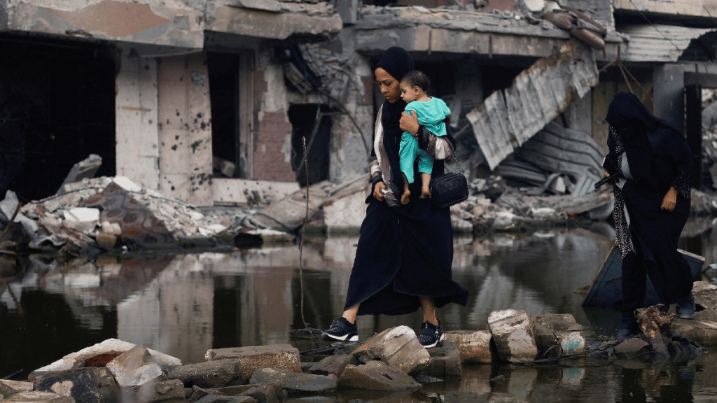 一名婦女抱着孩子在被毀的建築物旁。（路透社）