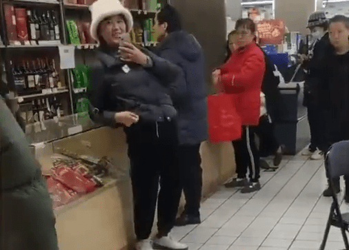 大妈要求超市店员道歉，围观者在拍摄。