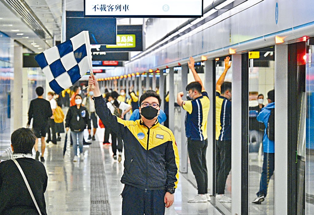 金鐘站東鐵綫月台人員,舉旗提示乘客已抵達終點站。