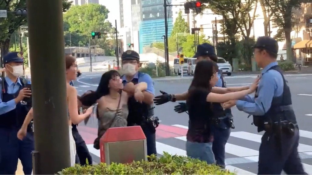 警員嘗試將兩人拉開，帶回行人路上，此時另一女子又出手推警員。