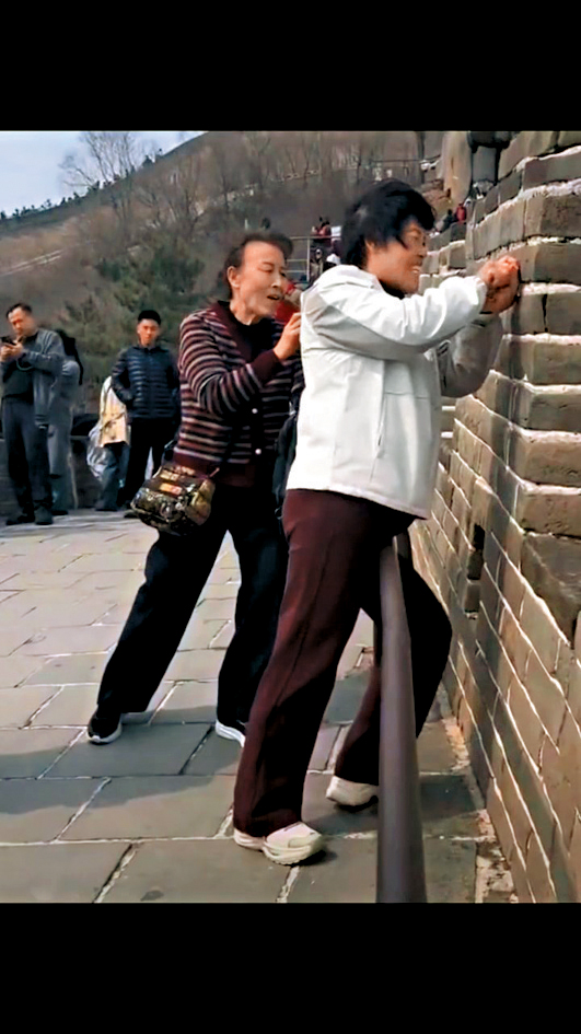 兩名中年女子在遊覽長城時刻字留名。