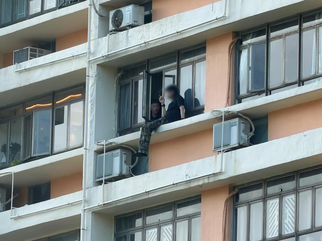 男子於中層單位窗外危坐。 男子於中層單位窗外危坐。