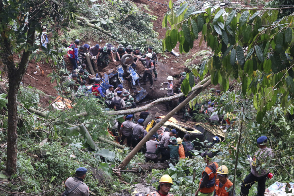 地震造成道路損毀，有車輛沖落山破，救援人員救出傷者。 AP圖
