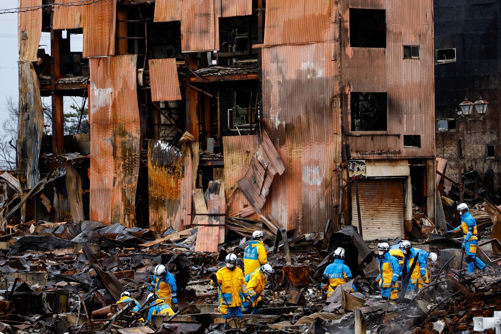 搜救人员在朝市通大火后的废墟中搜寻失踪者。路透社