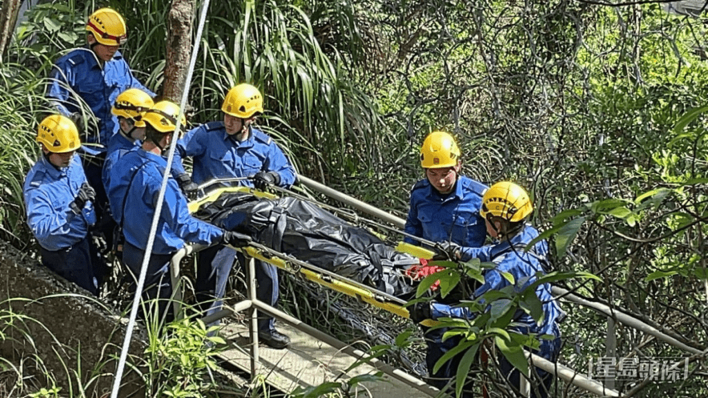 消防员将遗体抬下山。黎咏斯摄