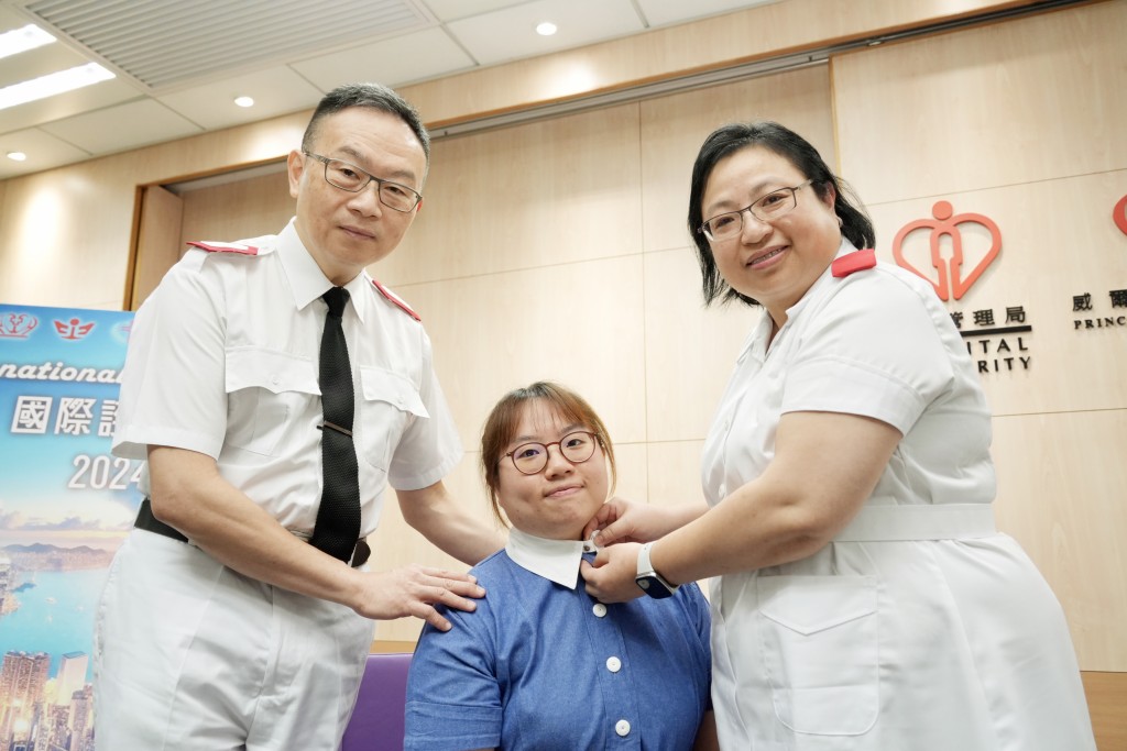 姚丽萍（右）亲手为女儿郑咏曦（中）戴上自己穿了多年的护士服颈钮，象徵传承。刘骏轩摄