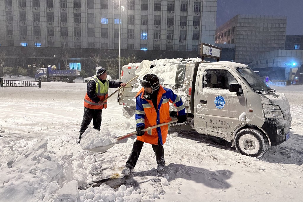 工人在哈爾濱市香坊區一街道上清掃積雪。 新華社