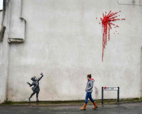 班克西新作小女孩手持弹弓射出一簇红花烟花,遭人涂鸦破坏。AP