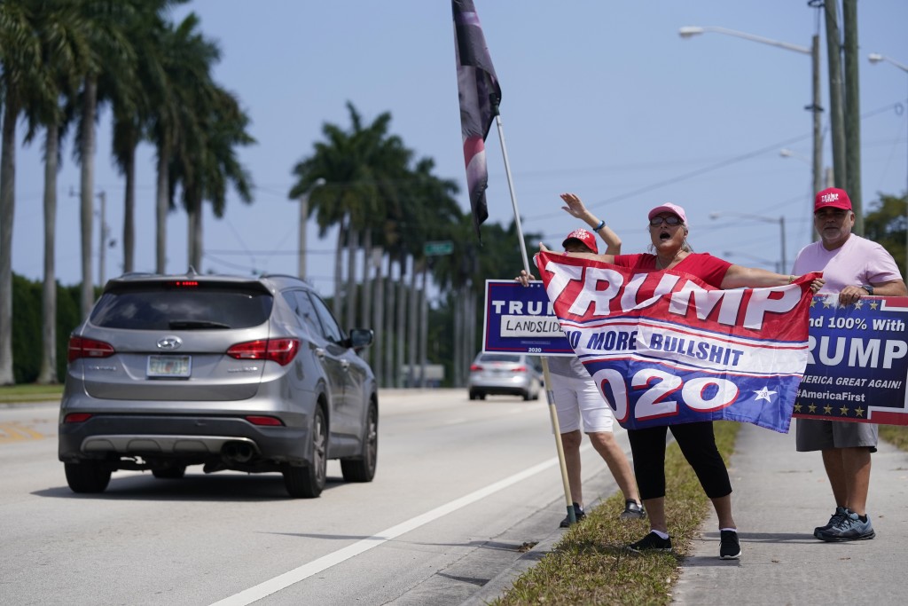 载着特朗普的车经过时，支持者挥舞著旗帜并举著标语。AP