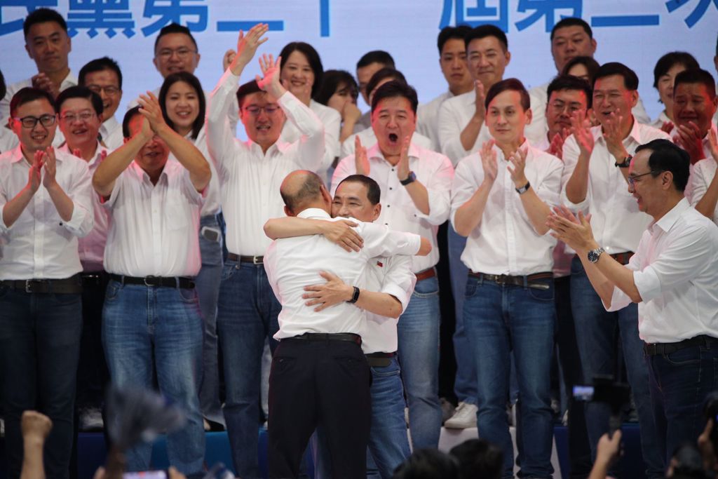 侯友宜（中前）与前高雄市长韩国瑜（中前背对者）在台上拥抱。中时