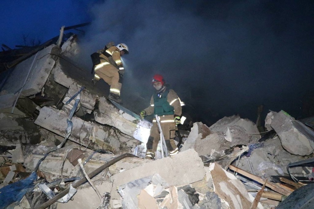 俄军空袭乌克兰中部城市第聂伯罗（Dnipro）一住宅区，救援人员在瓦砾中救出死伤者。（路透社）