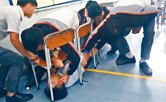 男生被人欺凌片段在網上瘋傳，可見他被按在椅下無法反抗。