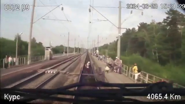 列车驶近，其中一人成功走上月台，一人还在路轨上。