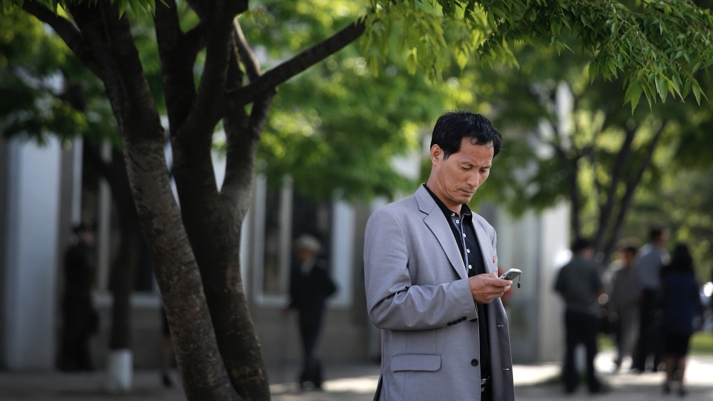 北韓男子在平壤街頭滑手機。 美聯社