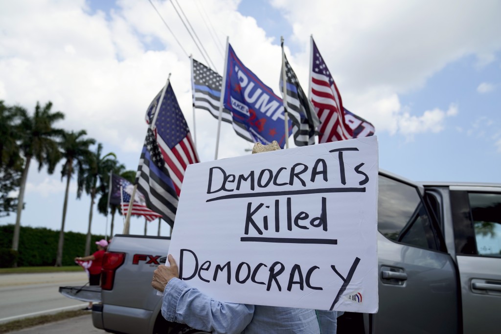 載着特朗普的車經過時，支持者揮舞著旗幟並舉著標語。AP