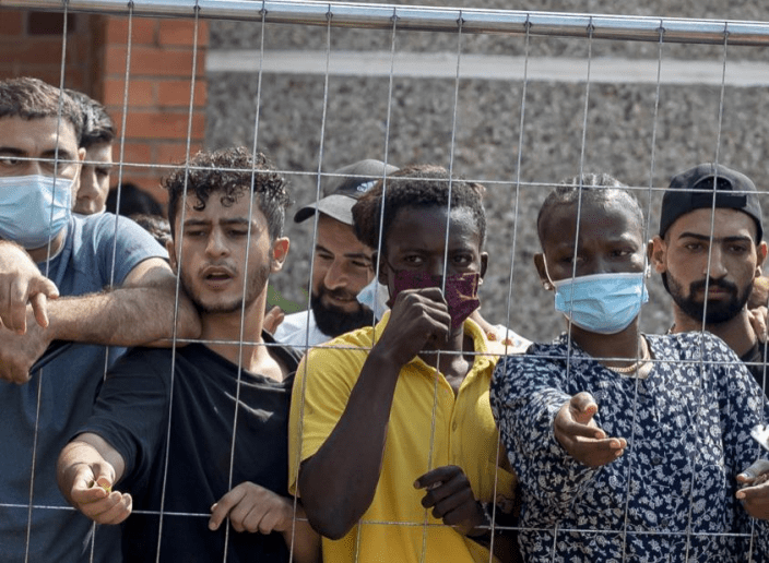 距离立陶宛维尔纽斯以南约145公里的Verebiejai村的难民营里，难民们站在栅栏后面等待购买一些东西。AP