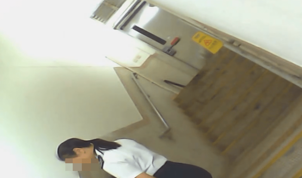 一名身穿食環署制服的女子獨自在梯間吸煙。網上片段截圖