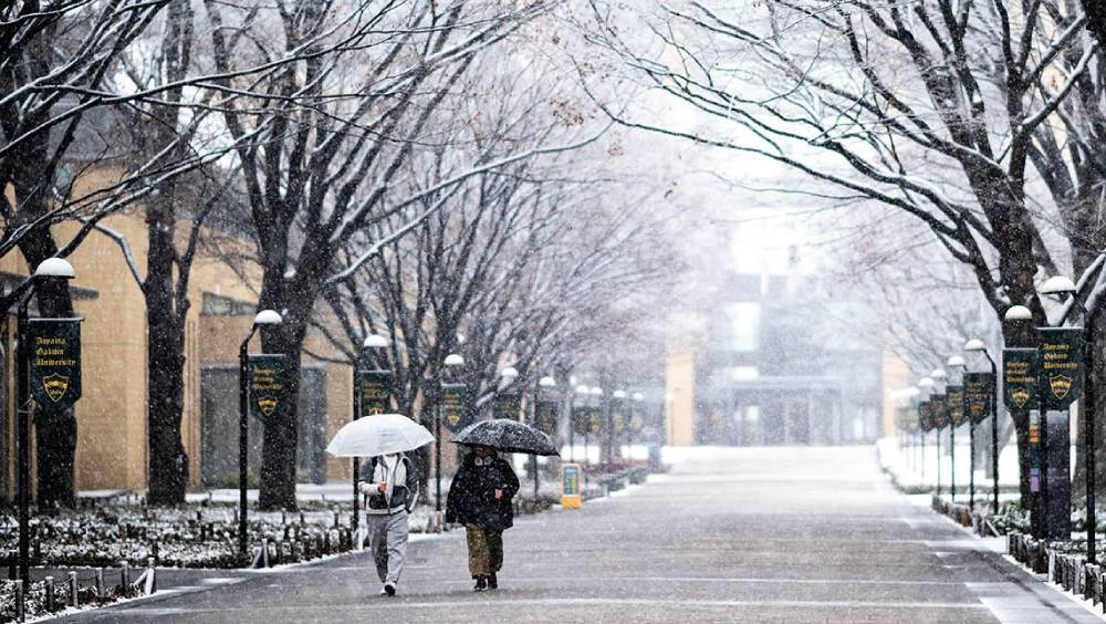 行人走在下雪的日本神奈川縣相模原市青山學院大學。 新華社