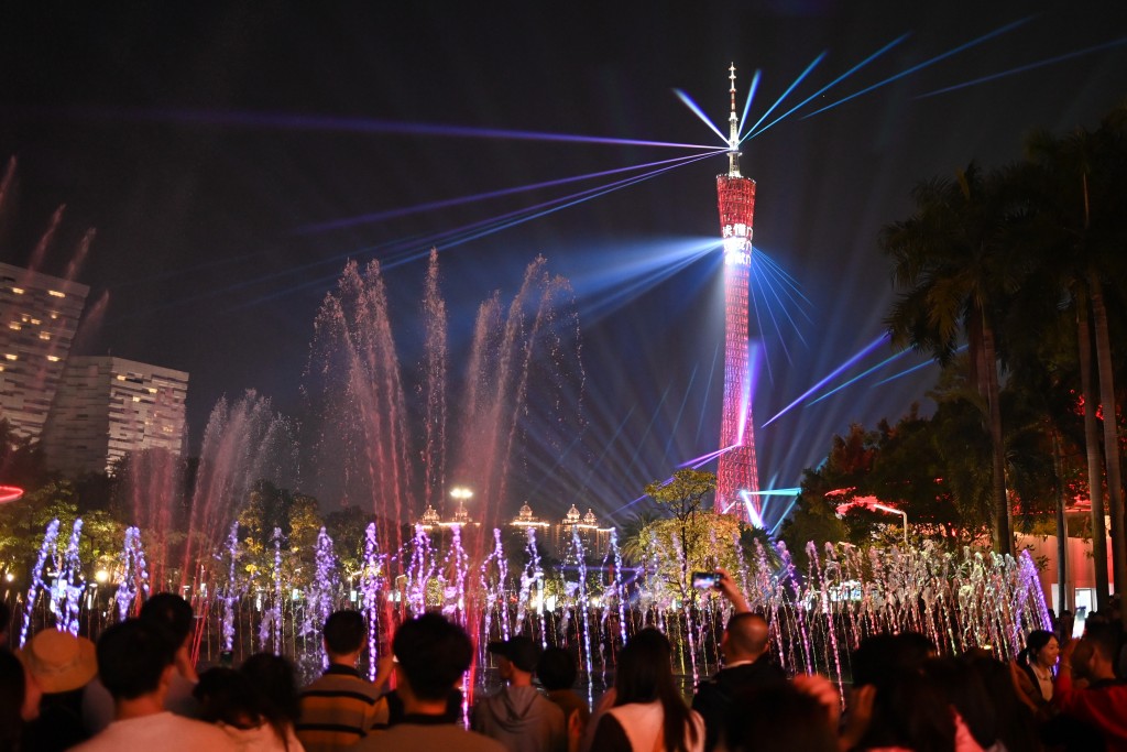 廣州塔的燈光表演與花城廣場音樂噴泉構成的水幕相融合，吸引遊客觀看拍照。中新社
