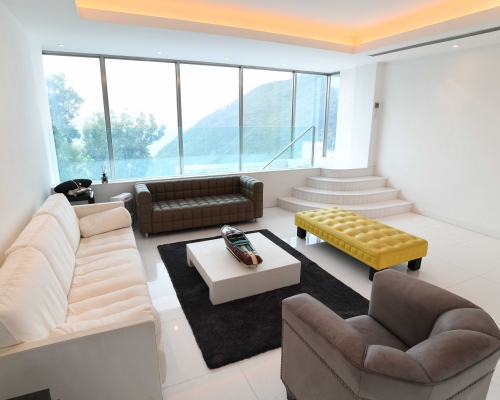 客廳擺放多組大型沙發，亦置黃色長椅，為簡約廳堂增添點綴。