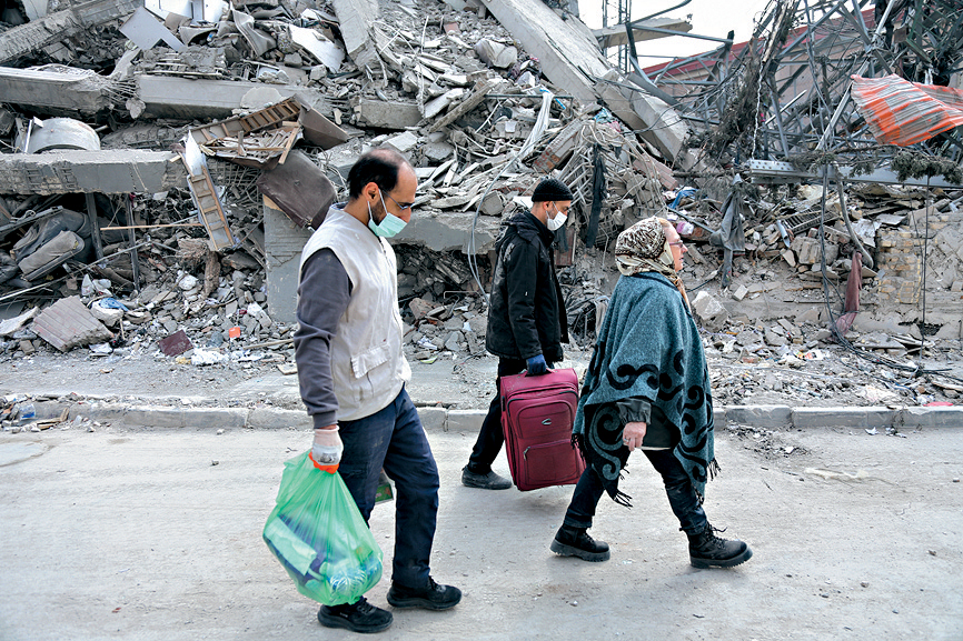在伊朗德黑兰，市民在颓垣败瓦前经过。