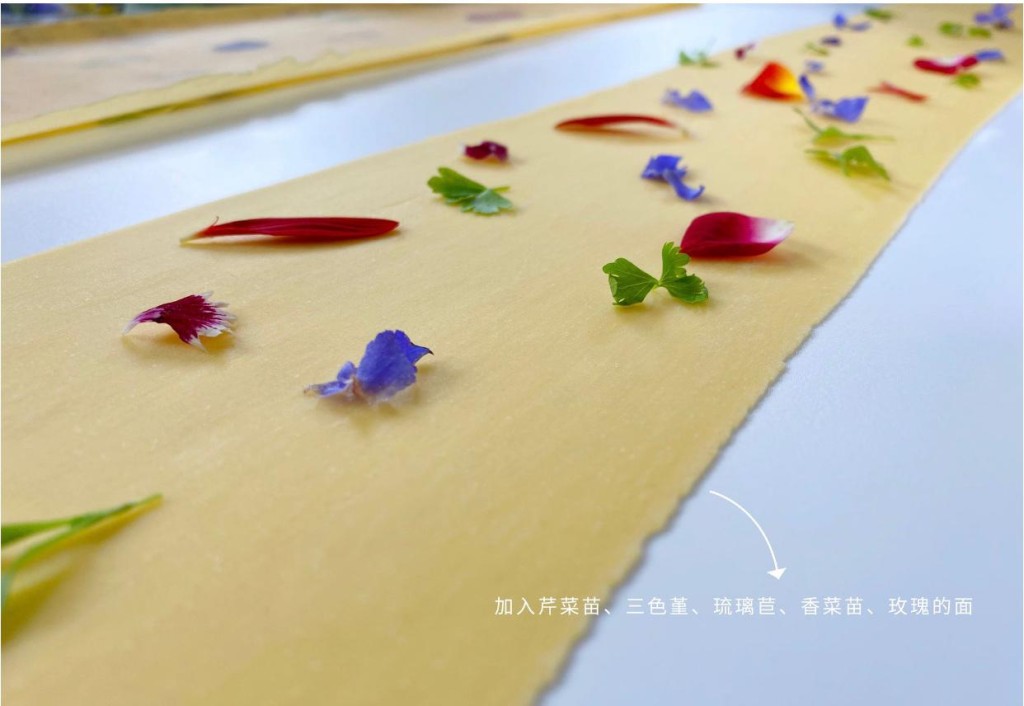 麵糰上放滿七彩的裝飾，經製麵機壓製後變成色彩繽紛的麵條。