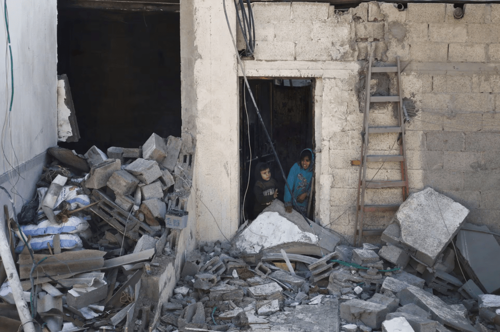 2024 年 2 月 7 日，拉法遭以軍空襲，巴勒斯坦兒童站在破敗房屋的現場。路透社