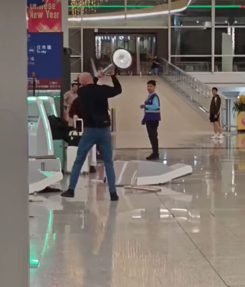 外籍漢拿起告示牌柱，擊向被推倒的櫃檯。fb香港突發事故報料區影片截圖