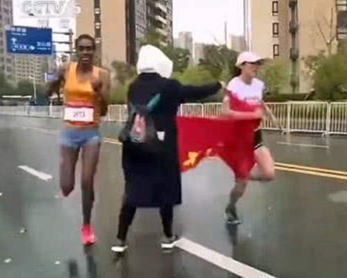 何引麗則被該女子攔住不得不接過國旗。影片截圖