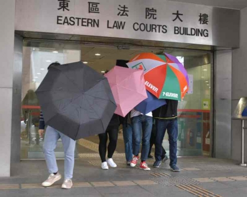 范俊文(紅色鞋)在傘陣遮掩下離開法院。