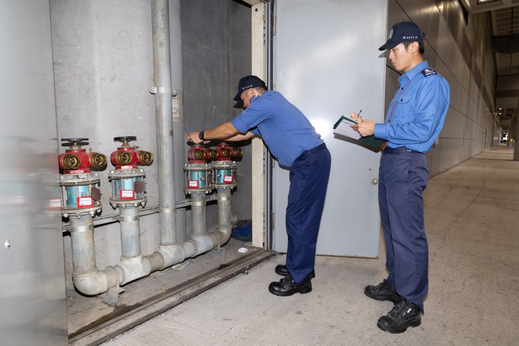 消防處人員檢查大廈消防栓／喉轆系統的消防入水掣的運作狀況。