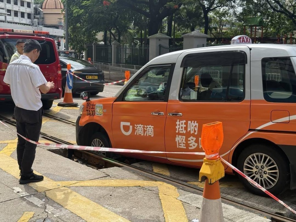 一轉的士衝入維修中的電車路軌，其前轆陷入坑內被困。網上圖片
