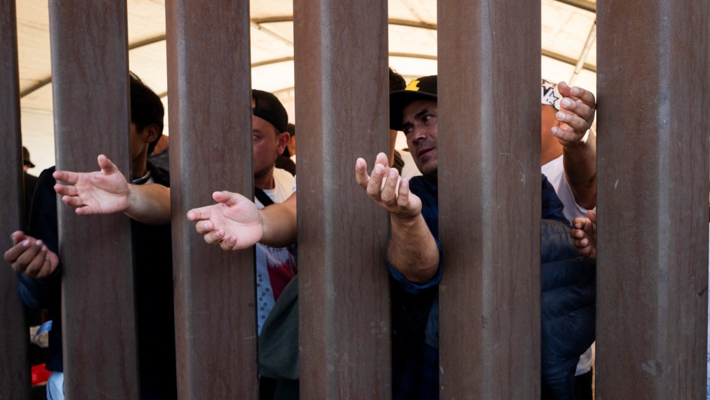 在墨西哥圣路易斯里奥科罗拉多，「第42条」 解除前，一些移民透过美墨边境围墙伸手取水。 路透社
