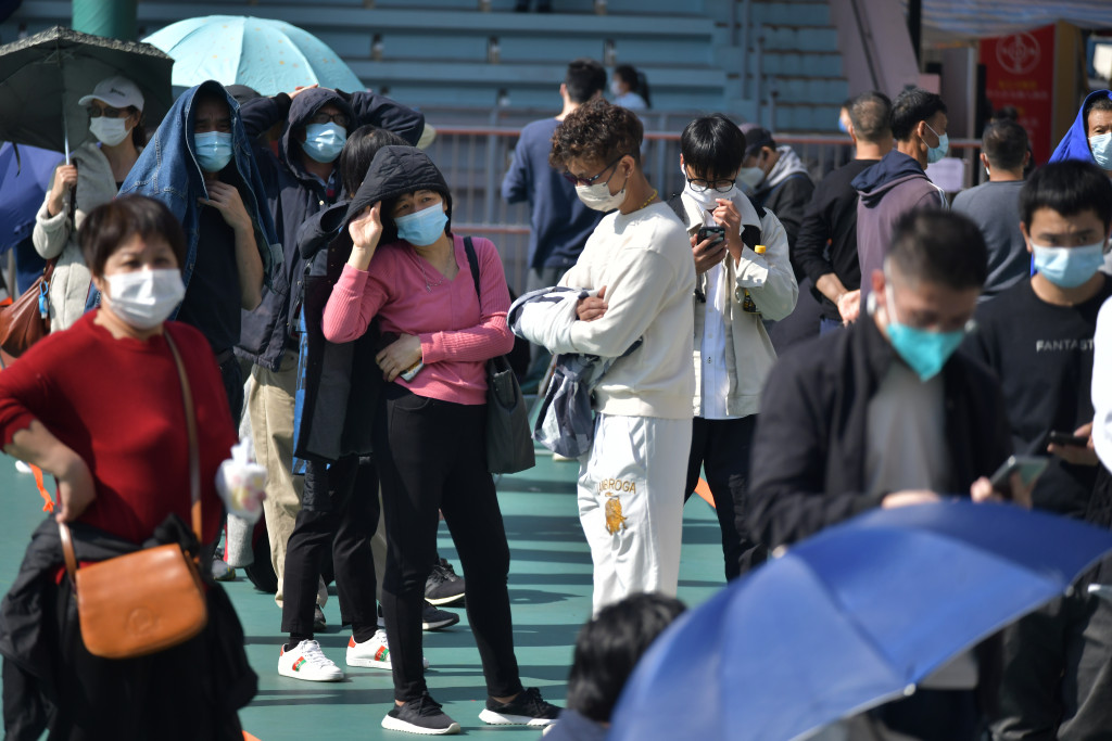 市民排队做检测，有人打伞遮挡阳光。陈极彰摄