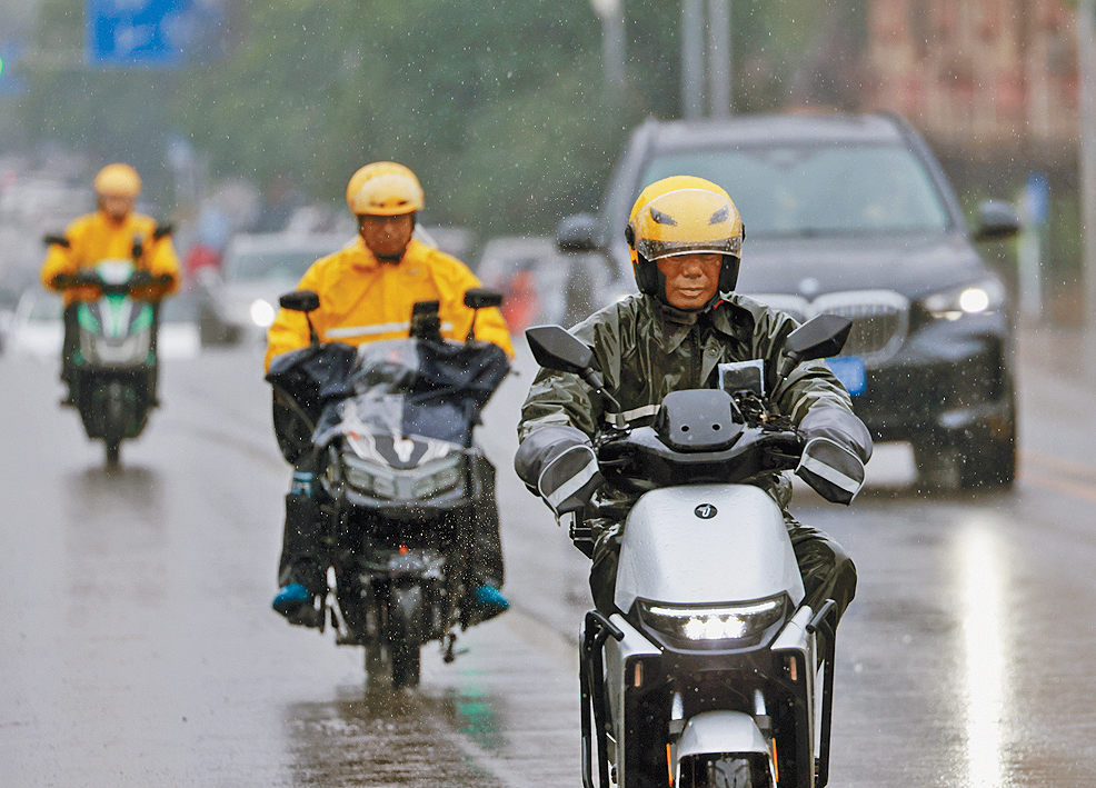 北京外賣員冒雨送餐。