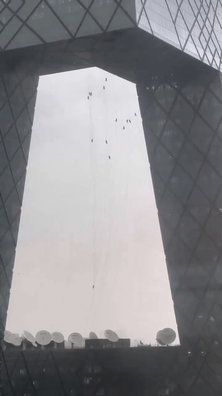 央视大楼15名洗窗工人高空随风摇摆。