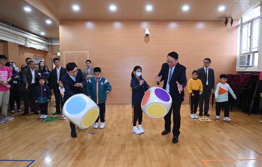 陈国基（前排右一）和孙玉菡（前排右四）与学童玩游戏。政府新闻处图片
