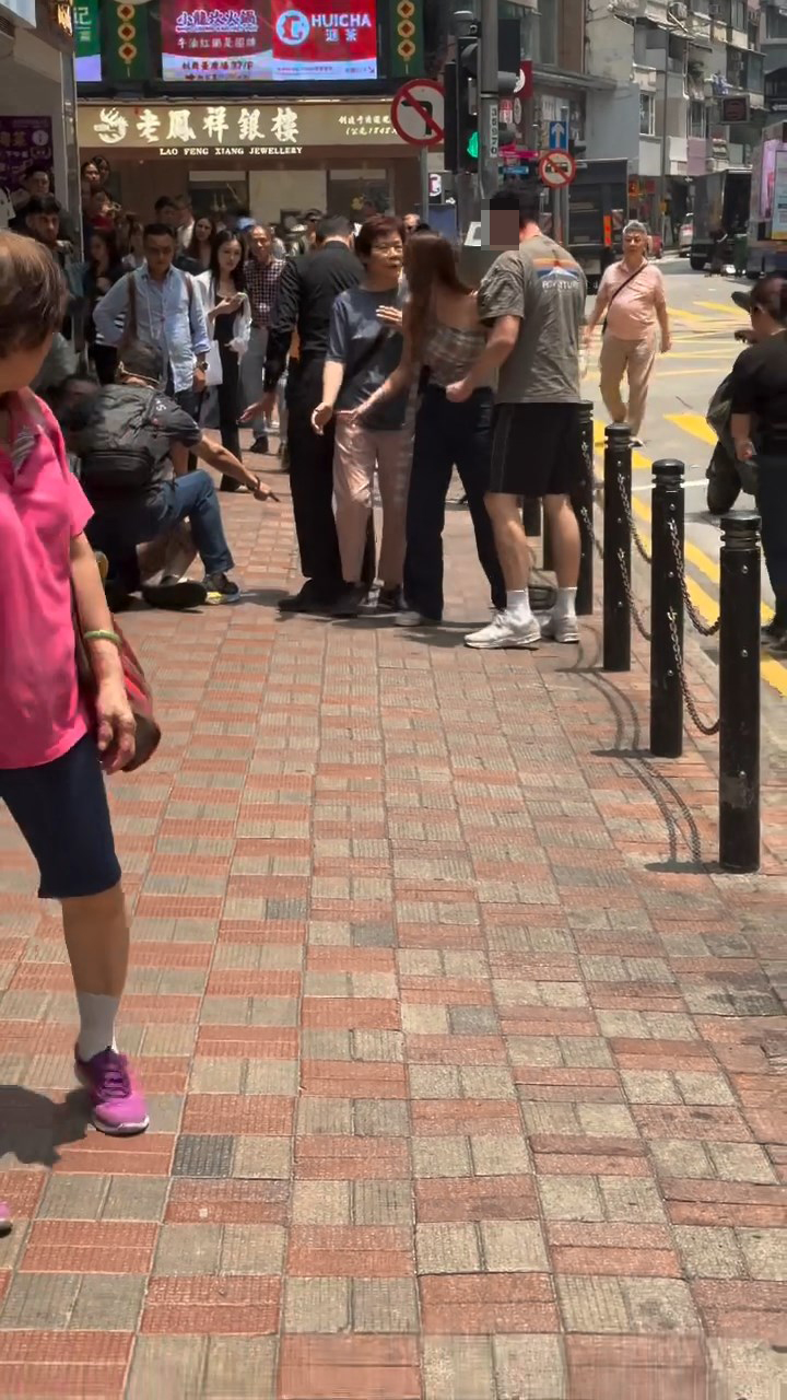 綠色衫的男子頭部受傷流血，與同行女子站在銅鑼灣廣場二期對開的欄杆旁邊。Threads@wkmik片段截圖