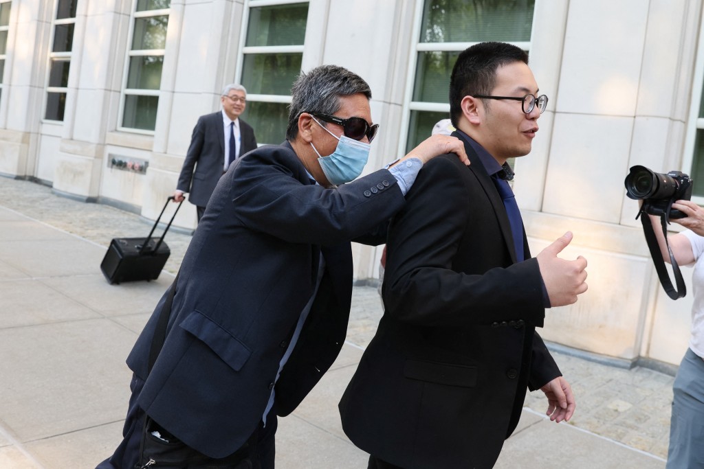朱勇（帶口罩者）步出法院時，躲避記者的拍攝。路透社