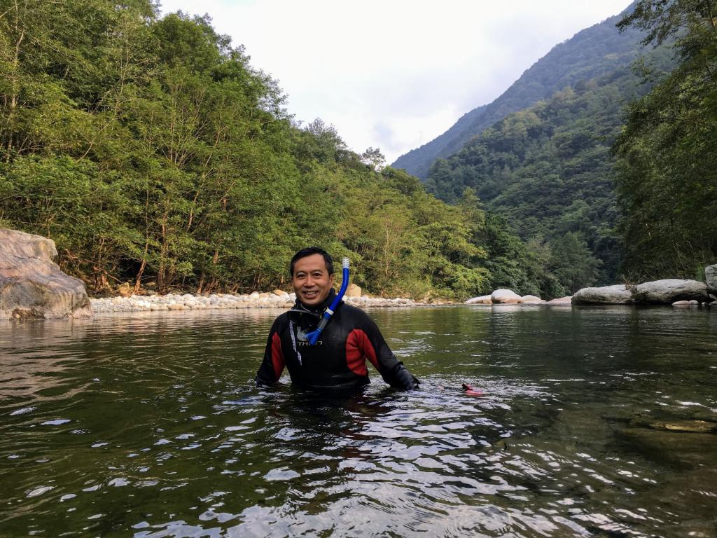 陈辈乐穿上潜水衣，在四川唐家河保护区的河中考察鱼类。