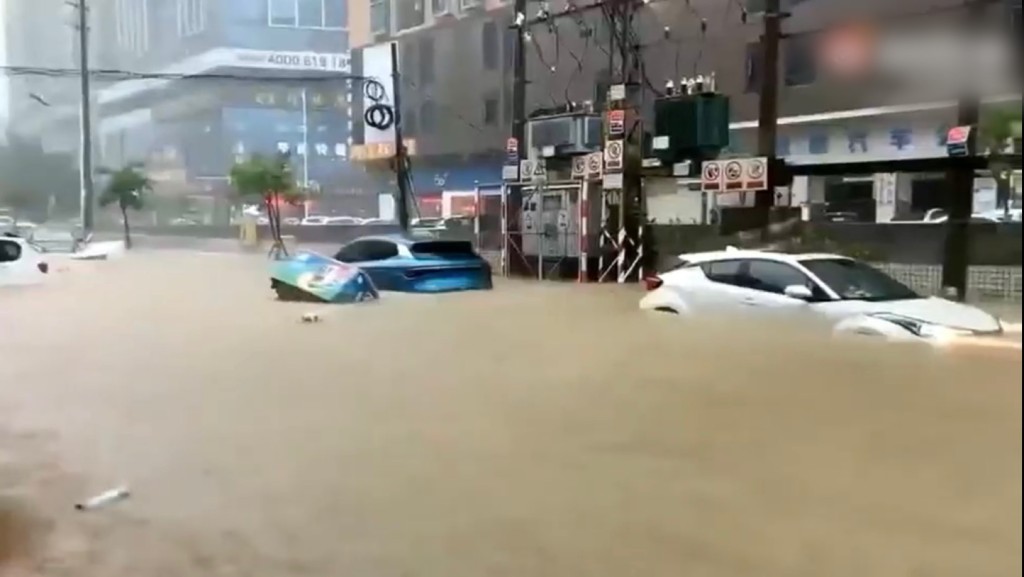 長安一處水浸,一輛藍色色沿路被沖走。