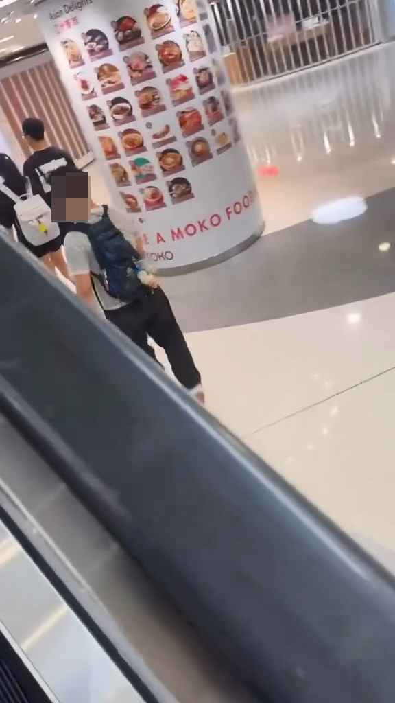 男子翻越玻璃欄杆,爬落扶手電梯中間的銀色蓋板,之後沿著蓋板慢慢爬行到下一層。Threads@showerrrjun片段截圖 男子翻越玻璃欄杆,爬落扶手電梯中間的銀色蓋板,之後沿著蓋板慢慢爬行到下一層。Threads@showerrrjun片段截圖