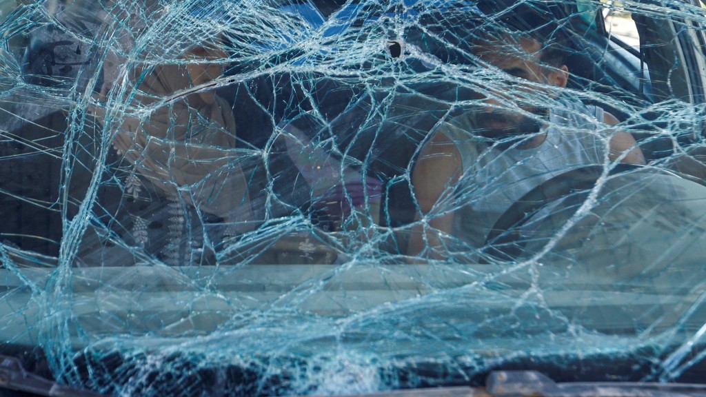 一對夫婦汽車擋風玻璃被空襲炸碎仍未棄車。 路透社